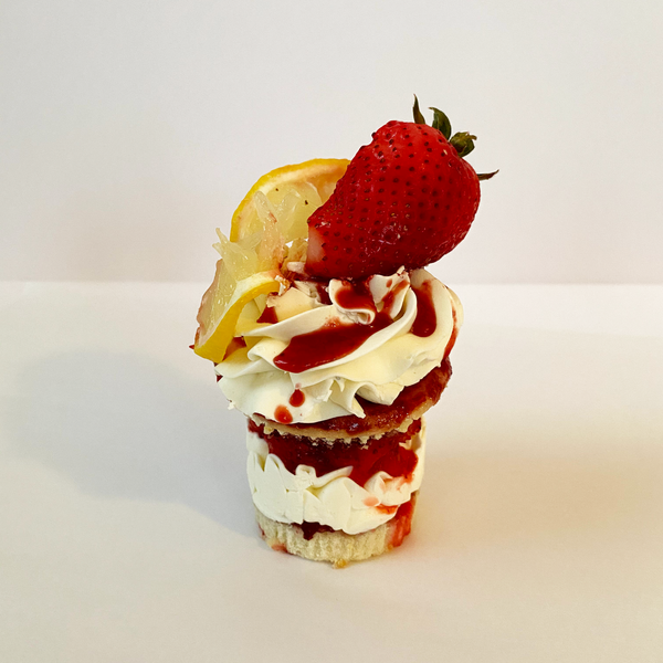Strawberry Lemonade stacked cupcake: Lemon cupcake split and filled with lemon italian meringue buttercream, and fresh chopped strawberries and topped with lemon buttercream, slice of lemon, half strawberry,  and strawberry drizzle.