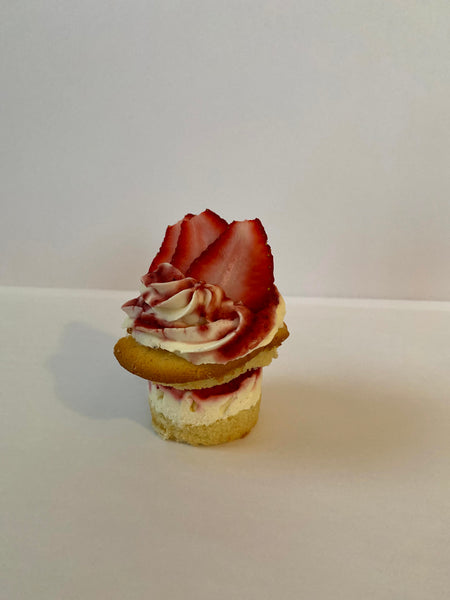 Strawberry Cheesecake stacked cupcake: vanilla cupcake with miniature strawberry cheesecake baked into the center split and filled with fresh chopped strawberries vanilla italian meringue buttercream and topped with vanilla italian meringue buttercream, sliced strawberries, and strawberry drizzle. 